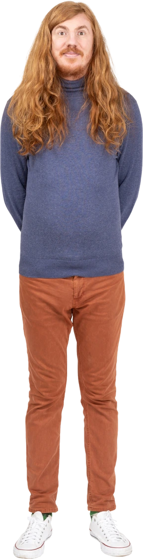 Front view of a young man in casual clothes standing with hands behind back