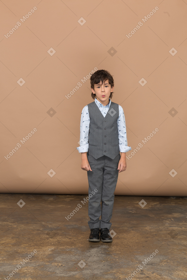 Вид спереди симпатичного мальчика в сером костюме, смотрящего в камеру
