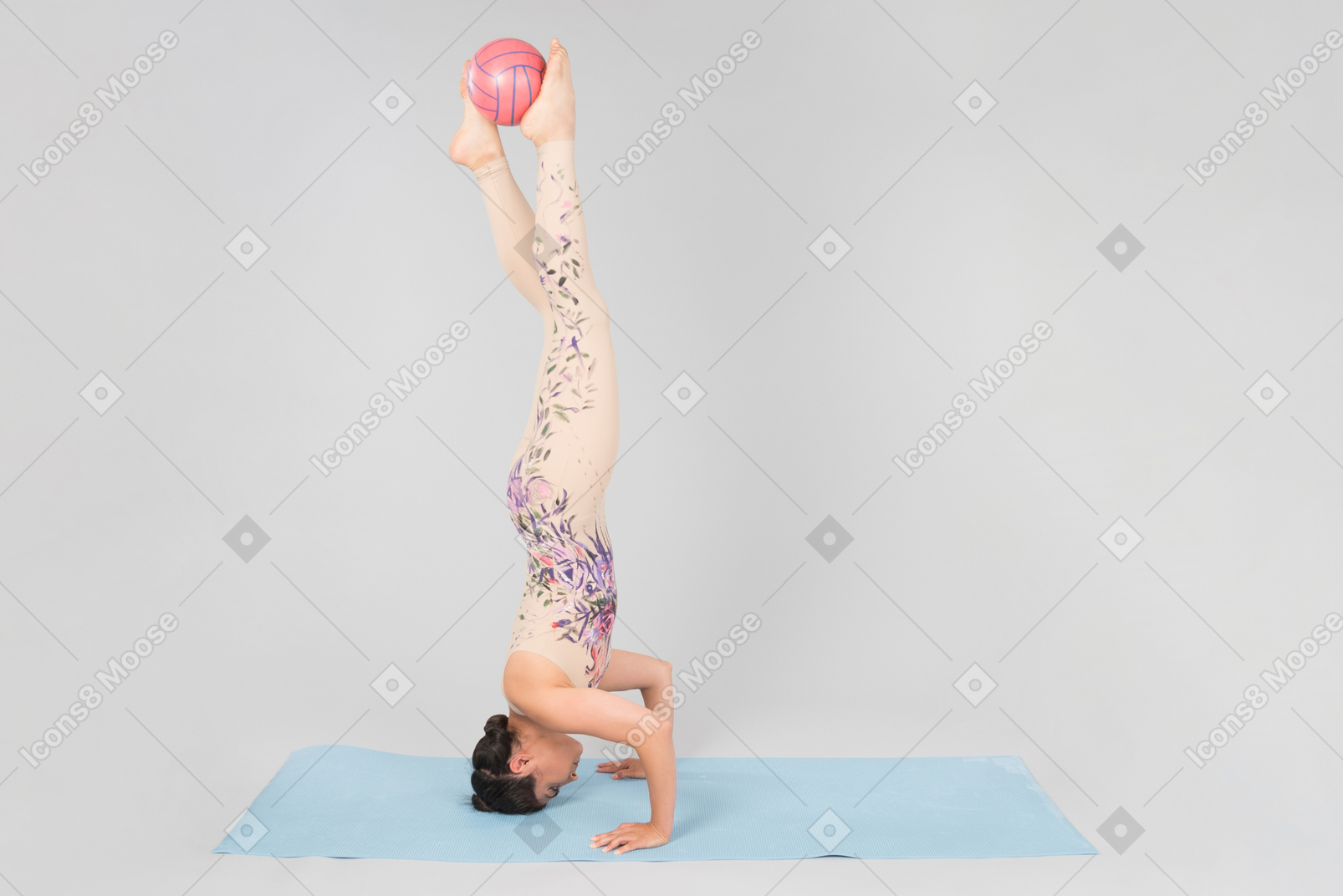 Young indian woman standing on the head on yoga mat and holding ball with legs up