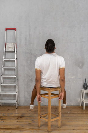 Back view of young man sitting on chair