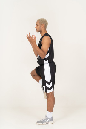 Vista lateral de um jovem jogador de basquete masculino meditando