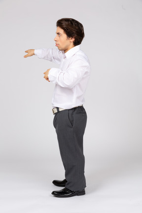 Side view of young man pointing with one hand