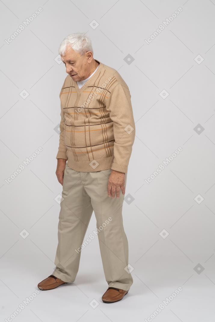 Vista frontal de un anciano con ropa informal mirando hacia abajo
