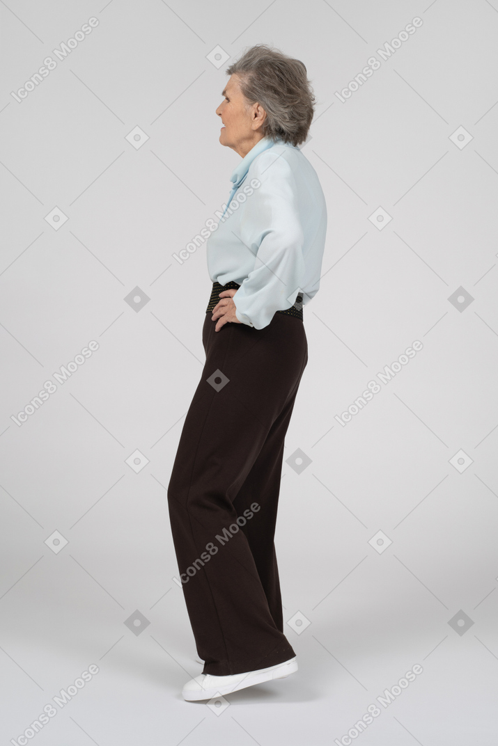 Vista lateral de una anciana con una mano en la cadera