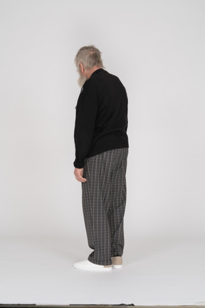Vista traseira do homem idoso em pé de calças quadriculadas