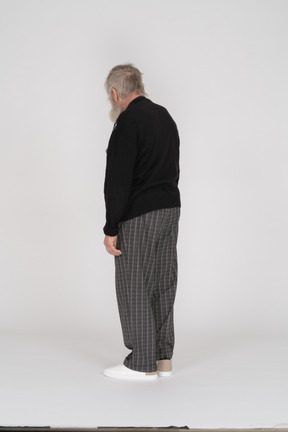 Rear view of elderly man in checkered trousers standing