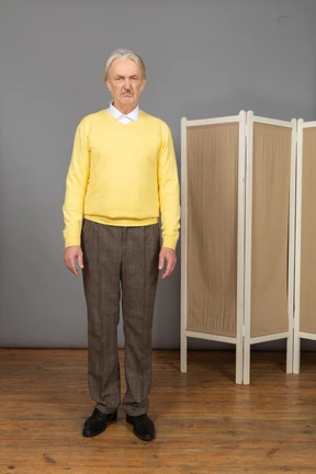 Front view of an old displeased man standing still