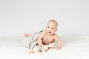 Baby girl covered in towel and holding a toy