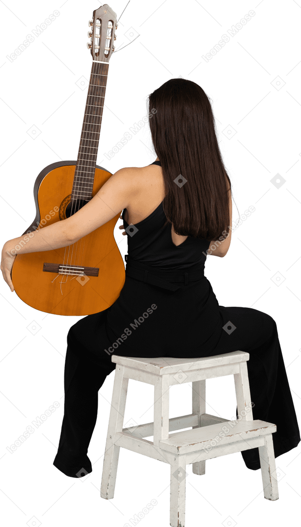 Vista posteriore di una giovane donna in abito nero che tiene la chitarra e seduto su uno sgabello