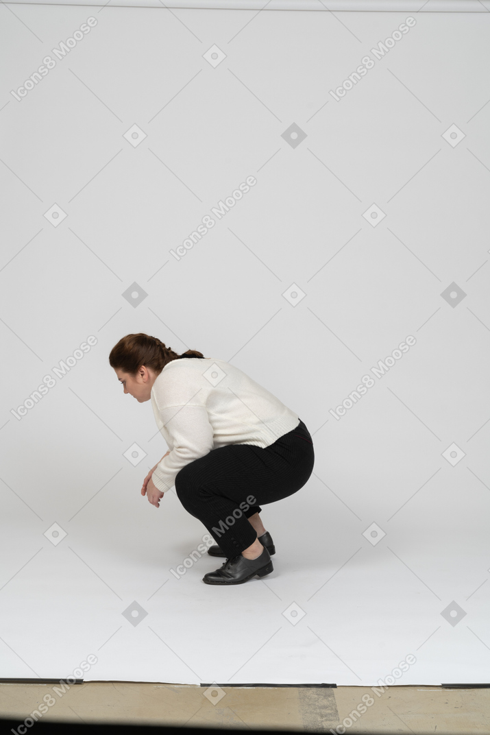Vista lateral de una mujer regordeta en ropa casual en cuclillas