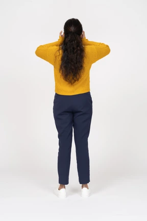 Rear view of a girl in casual clothes covering ears with hands