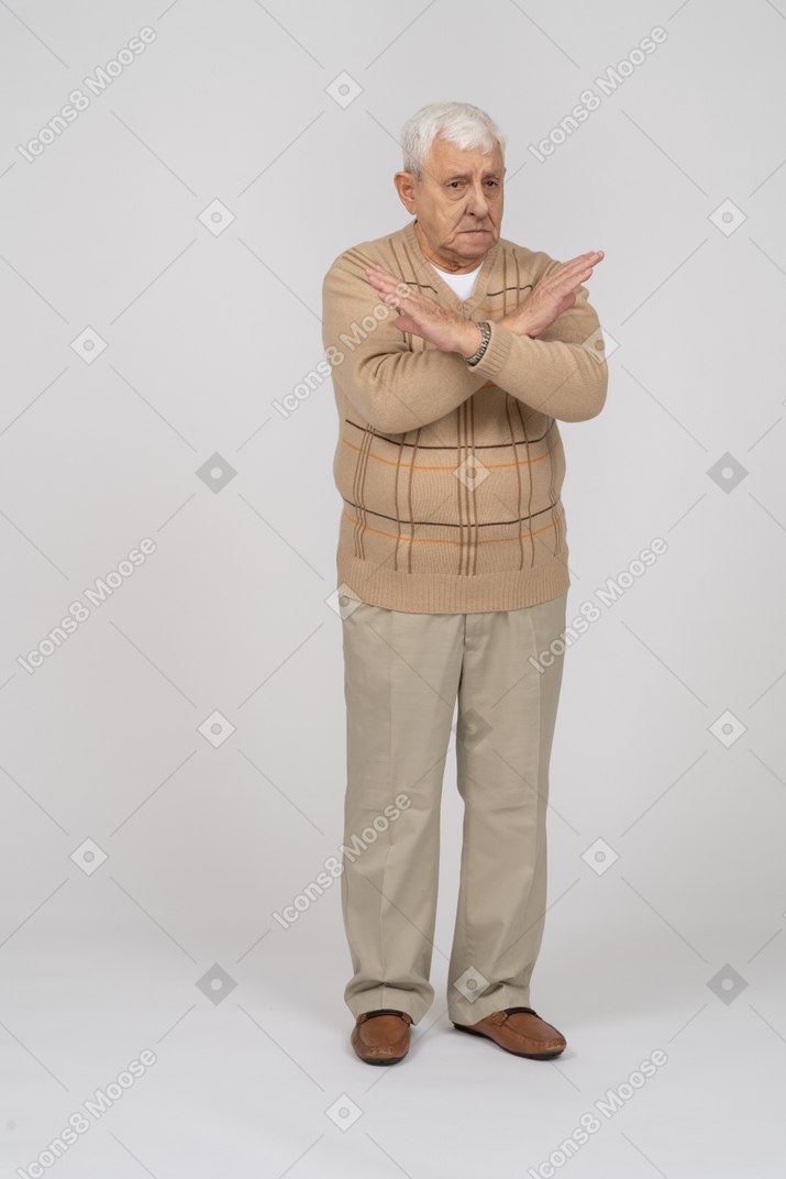 Front view of a sad old man in casual clothes showing stop gesture
