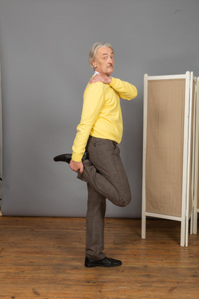 一位老人，抚摸他的肩膀时按住他的脚踝的侧视图
