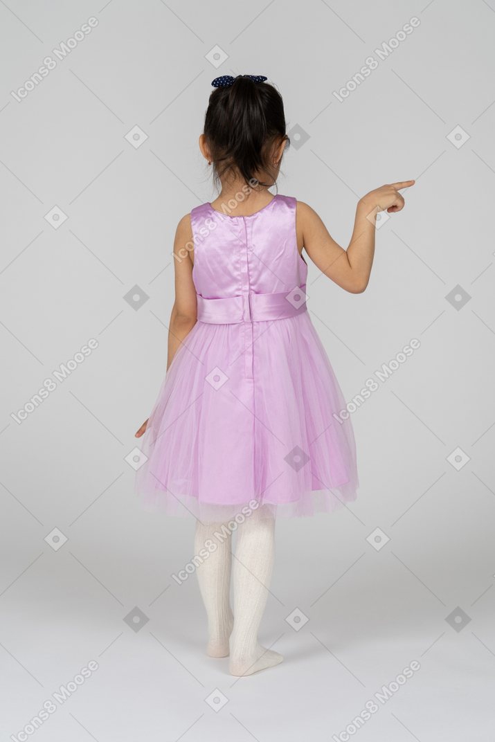 Back view of a little girl in a tutu dress pointing right
