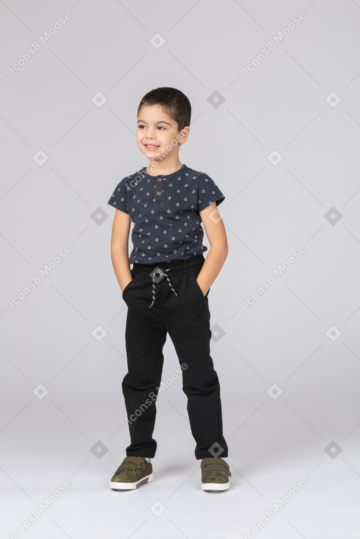 Front view of a happy boy posing with hands in pockets