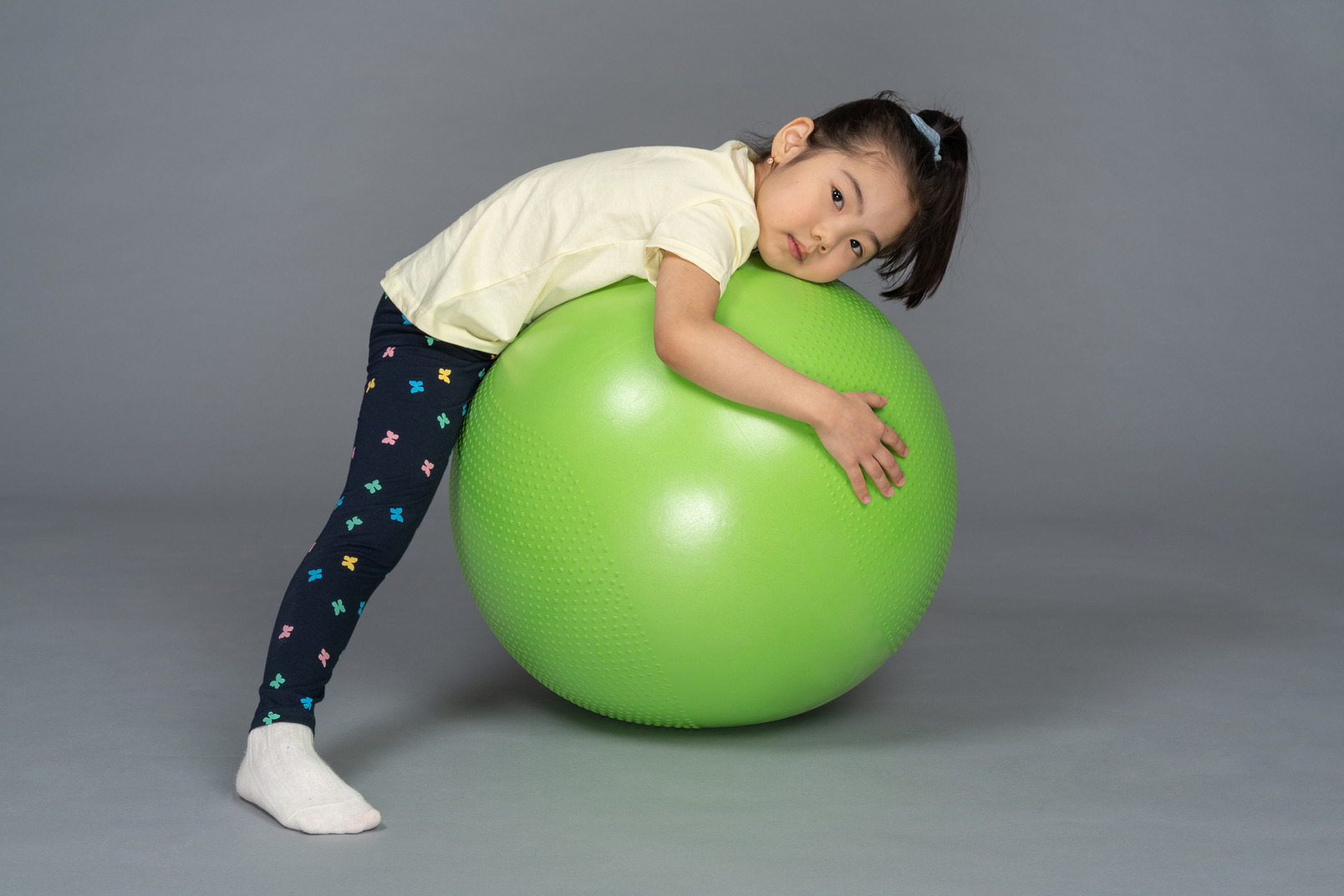 Little girl lying on a green fitball on the stomach