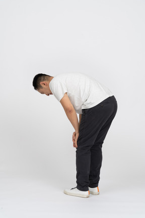Vista lateral de un hombre agachándose y tocando la rodilla lastimada