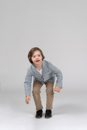 Young boy in jacket and pants crouching down