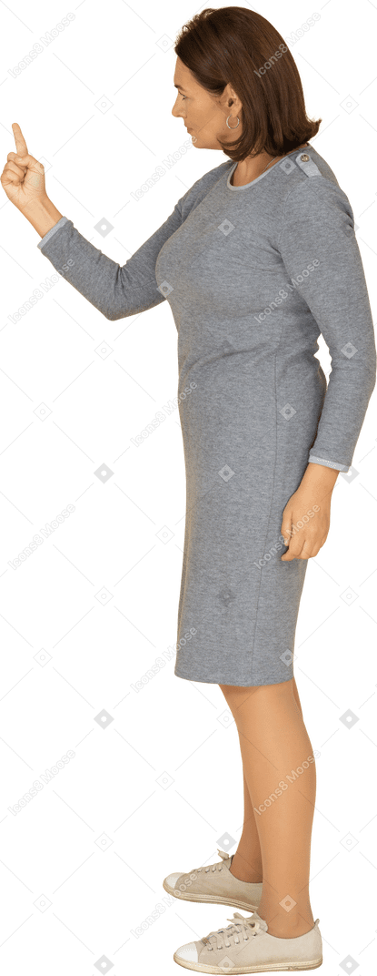 Vista lateral de uma mulher de vestido cinza apontando para cima com um dedo