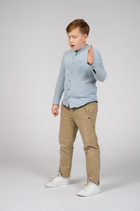 Niño con camisa azul de pie y hablando de algo