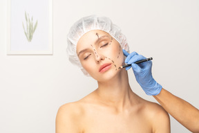 Young woman's face being marked for surgery