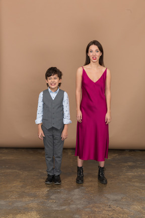 Vue de face d'un garçon et d'une femme souriants en robe rouge