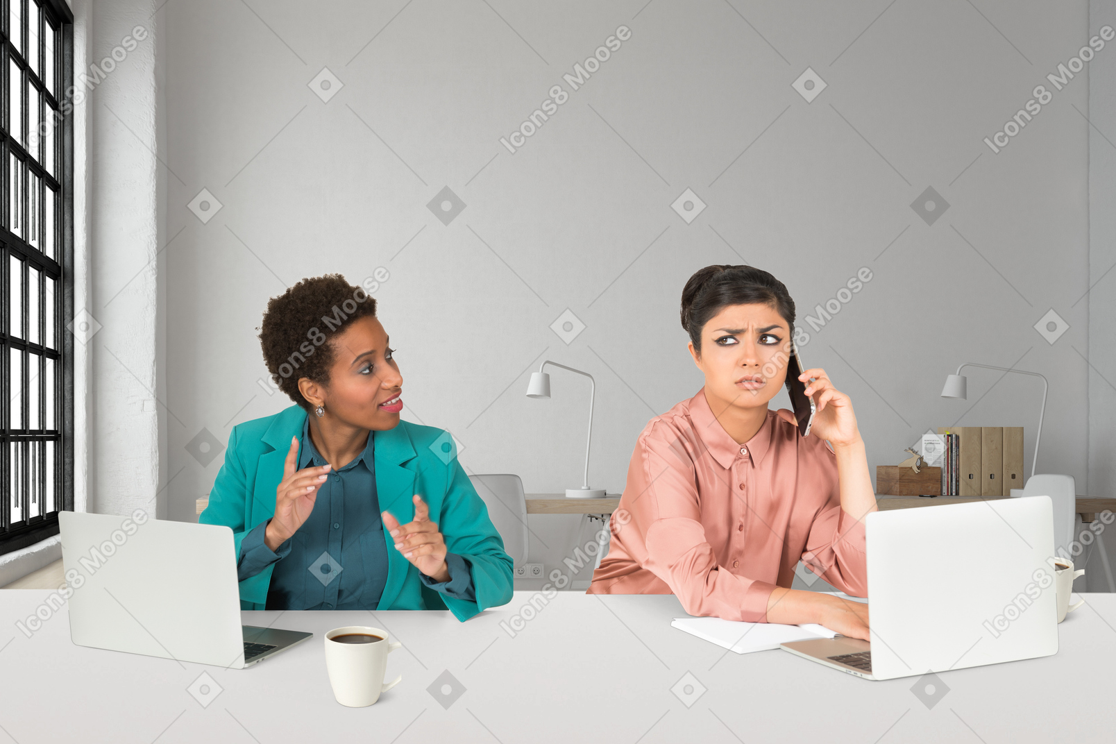 Two women sitting at a table with laptops