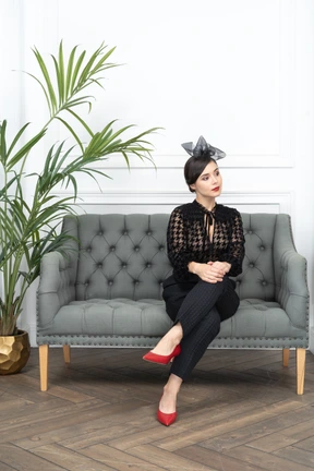A woman sitting on top of a couch next to a potted plant