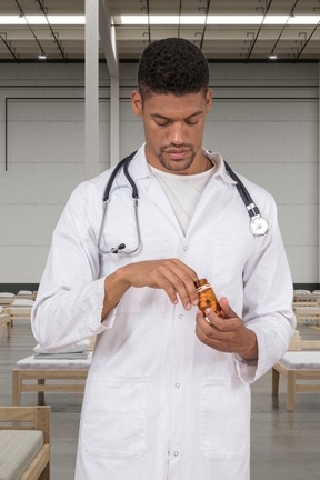 A male doctor taking pills out of the pill bottle