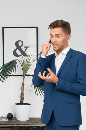 A man in a blue suit talking on a cell phone