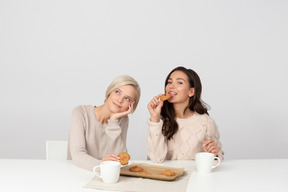 Mulheres jovens comendo biscoitos caseiros e bebendo café