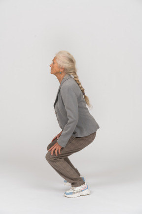 Side view of an old lady in suit squatting