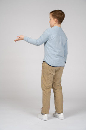 腕を伸ばして立っている少年の背面図