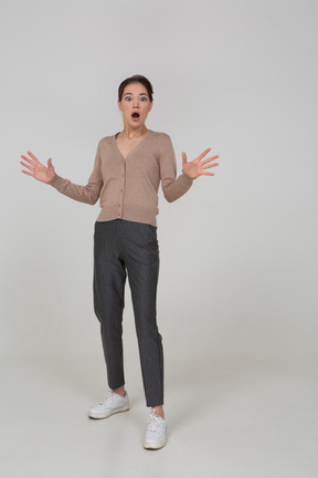 Front view of an astonished gesticulating young female in beige pullover