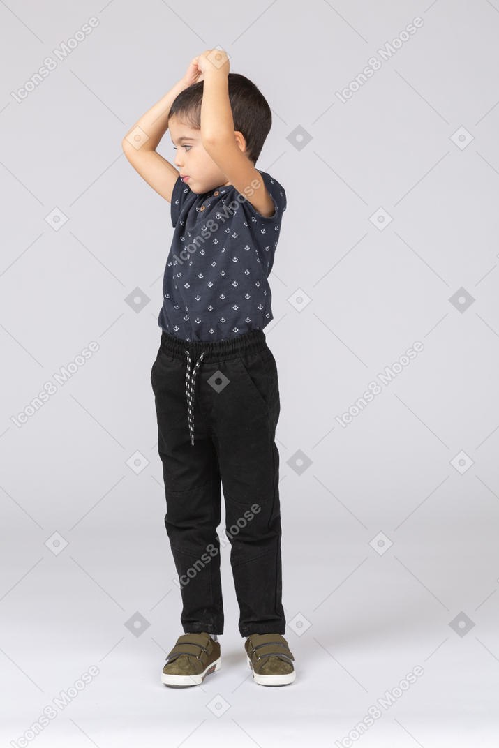Vista frontal de um lindo menino posando com as mãos acima da cabeça
