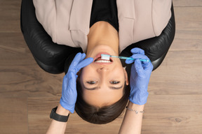 Женщина в кресле стоматолога чистит зубы