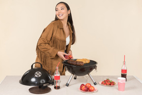 Young asian woman holding fruits and standing near grill