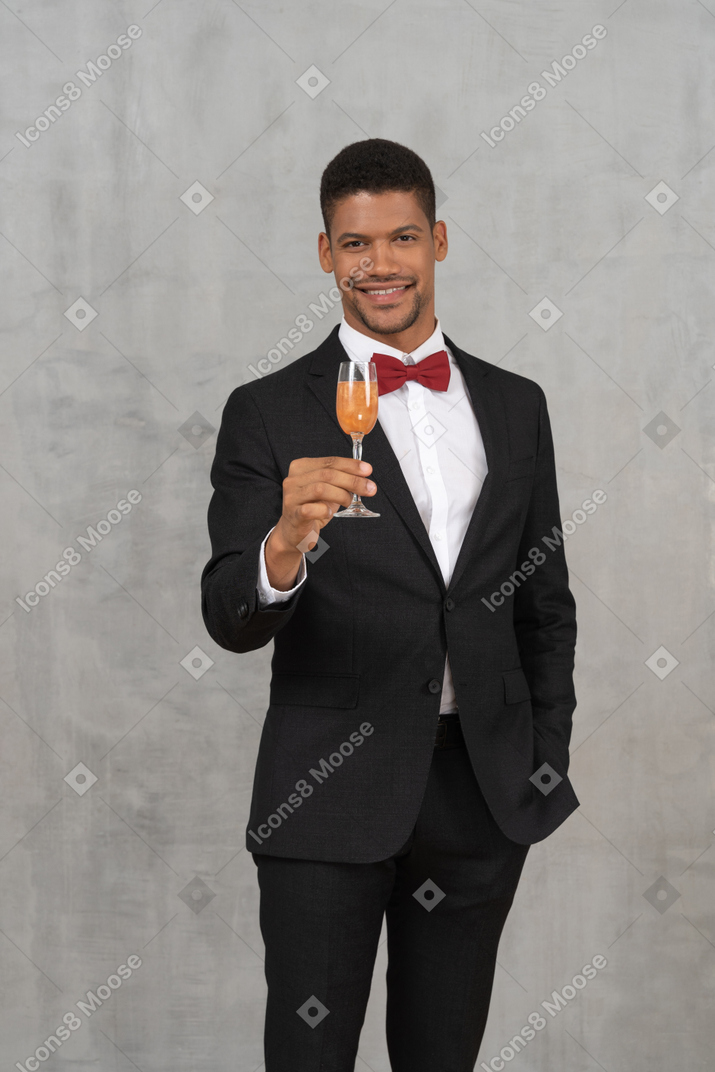 Young man with champagne glass smiling widely and looking at camera
