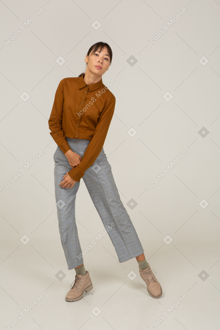 一位身着马裤和上衣的亚洲年轻女性跳舞的前视图