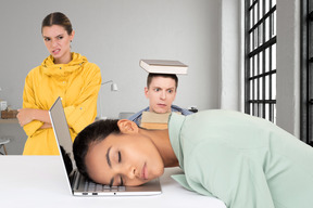 Office workers watching their colleague sleep on top of a laptop 