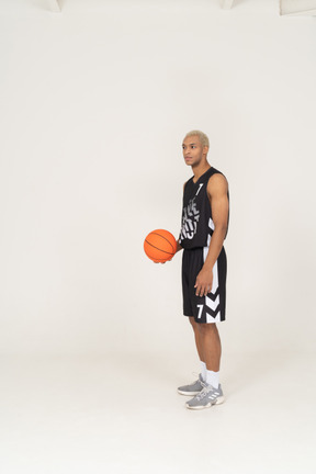 Three-quarter view of a young male basketball player holding a ball