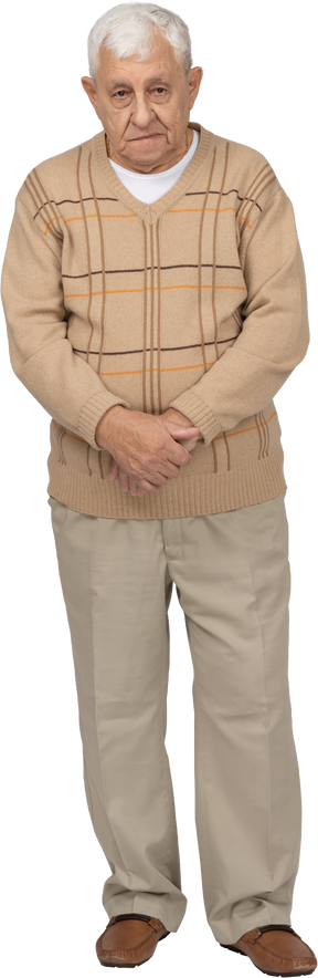Front view of an old man in casual clothes standing still and looking at camera