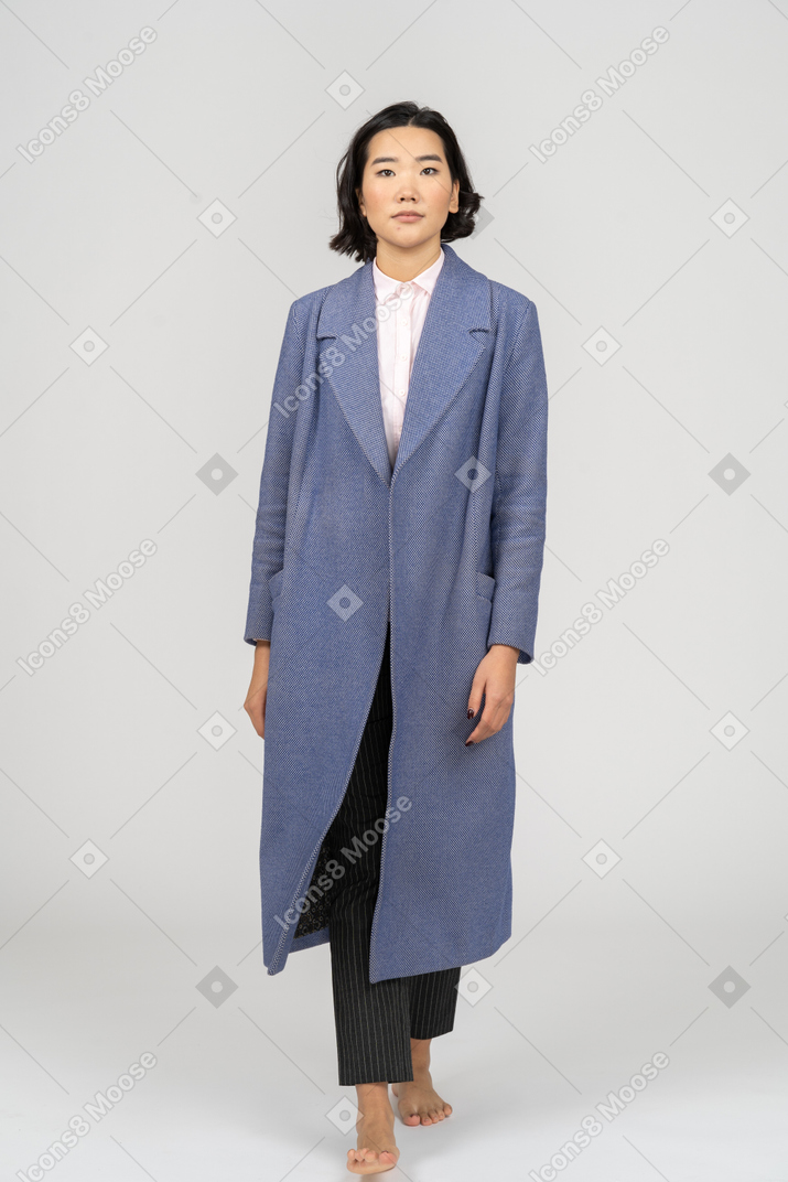 Business woman in coat looking at camera and walking