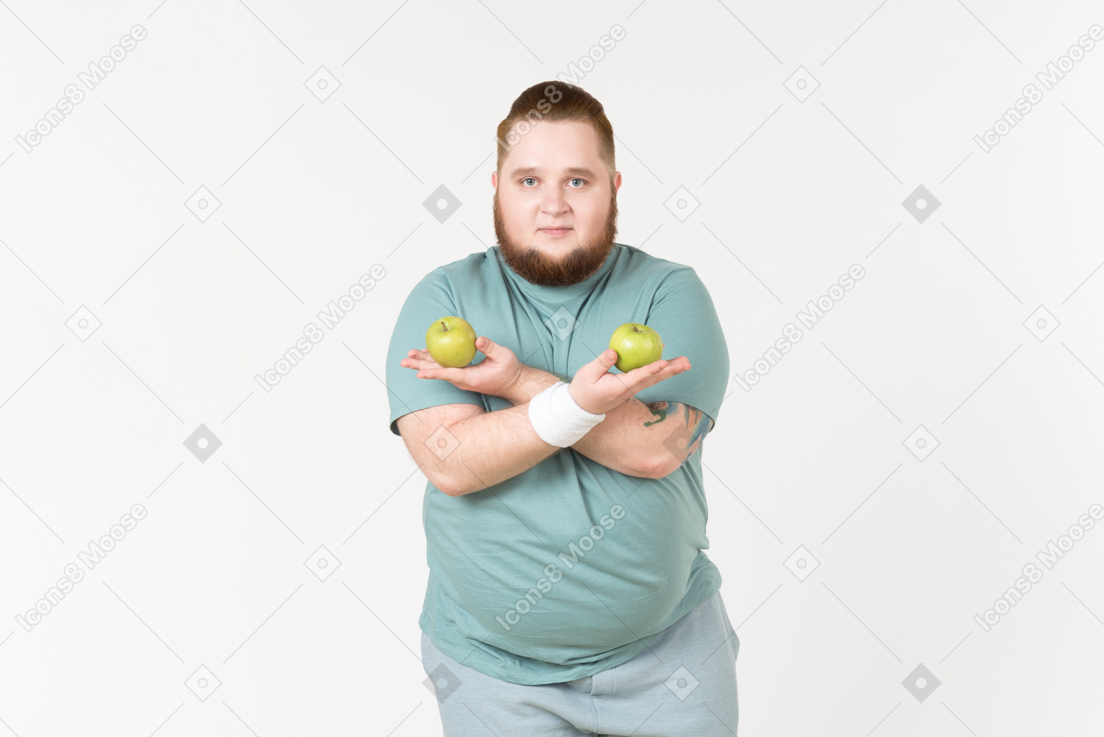 Overweight man in sportswear holding hands crossed and holding apples