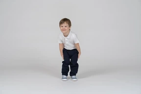 Cheerful little boy standing with his hands on his kneepits