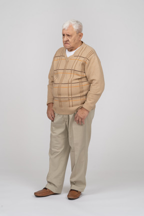 Front view of a sad old man in casual clothes standing still
