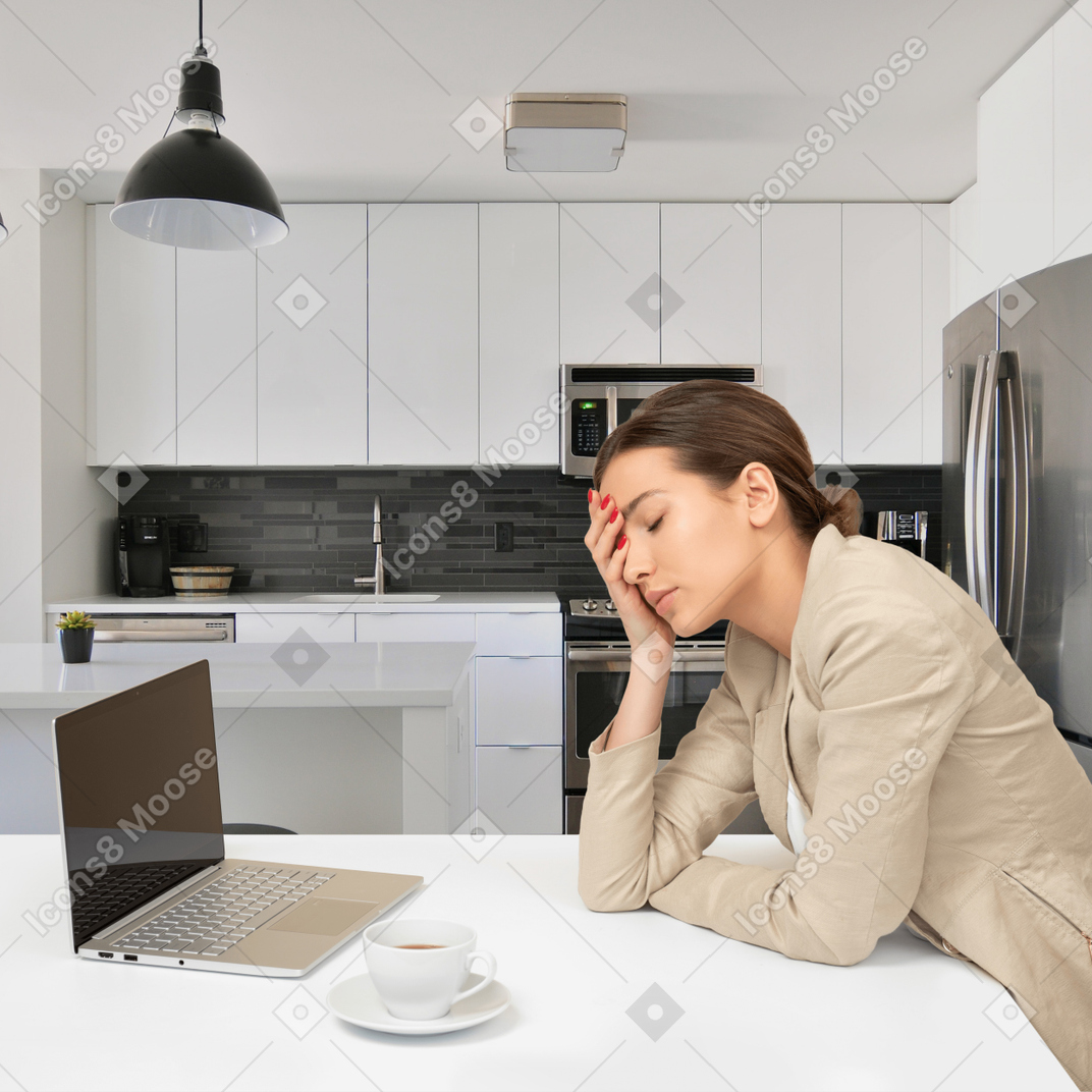A woman sitting at a kitchen table with a laptop