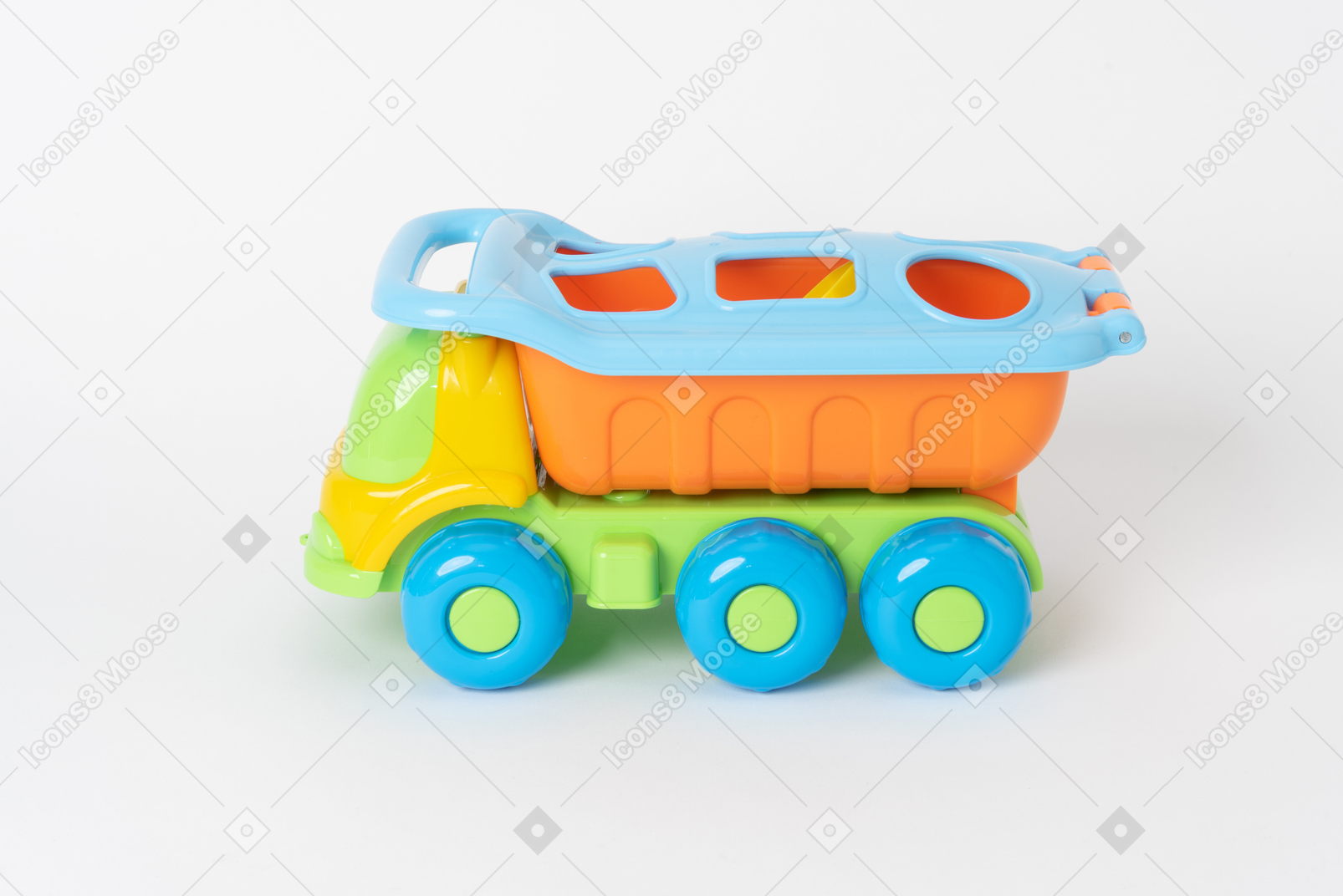 Un colorido camión volquete de juguete de pie contra un fondo blanco liso