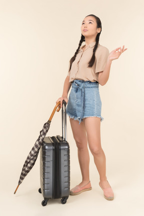 Jeune femme avec valise et parapluie en levant