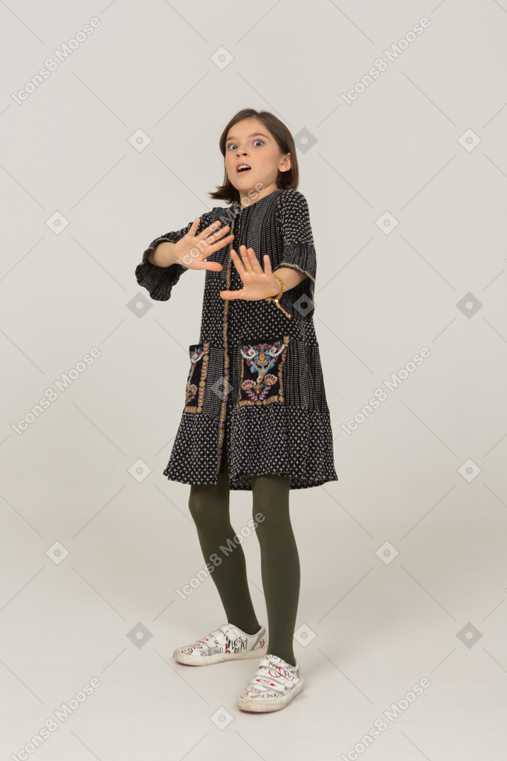 Vista frontale di una bambina in abito che allunga le braccia